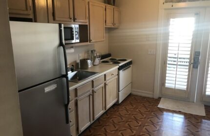 Kitchen in New Orleans house at a gay-friendly hotel. Stainless steel fridge, oven, and microwave. Cabinets, sink, and patterned floor.
