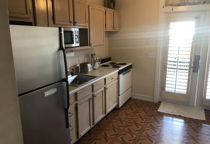 Kitchen in New Orleans house at a gay-friendly hotel. Stainless steel fridge, oven, and microwave. Cabinets, sink, and patterned floor.