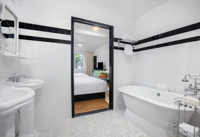 Axel Beach Miami gay-friendly hotel room. Bathroom with black stripes, tub, and sinks. Bedroom visible through open door. Modern design.