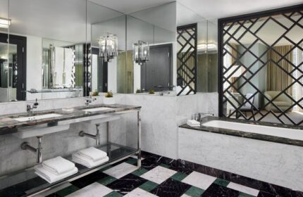 W Miami gay-friendly hotel bathroom. Double sinks, marble countertops, and a geometric screen separating the tub area. Upscale travel.
