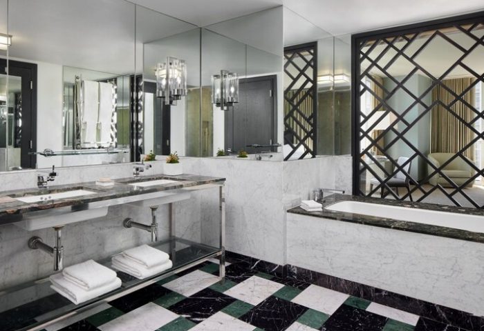 W Miami gay-friendly hotel bathroom. Double sinks, marble countertops, and a geometric screen separating the tub area. Upscale travel.