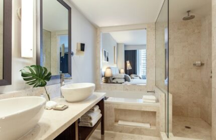 Kimpton EPIC Hotel's bathroom with double sinks, a bathtub, and a glass-enclosed shower. Gay-friendly hotel with modern design.