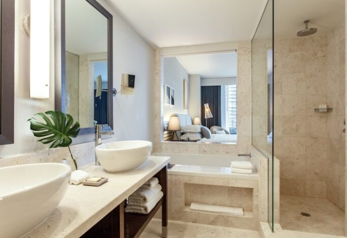 Kimpton EPIC Hotel's bathroom with double sinks, a bathtub, and a glass-enclosed shower. Gay-friendly hotel with modern design.