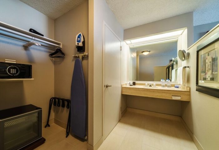 Hyatt Regency Miami gay-friendly hotel room detail. Closet with safe, iron, ironing board, and fridge. Bathroom area with large mirror and counter.