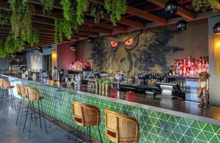 25hours Hotel One Central bar area. Green tiled bar front, monkey mural, hanging plants. Gay-friendly hotel, travel advice for gay men.