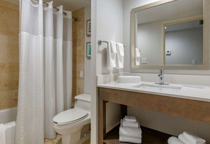 Comfort Inn & Suites Downtown Brickell-Port of Miami gay-friendly hotel bathroom. Toilet, sink, mirror, towels, and shower with curtain are visible.