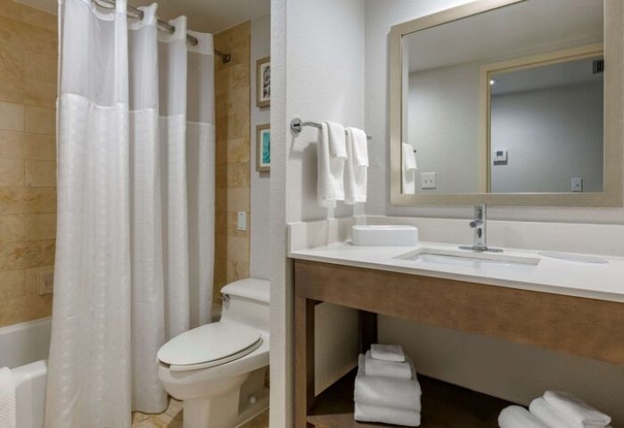 Comfort Inn & Suites Downtown Brickell-Port of Miami gay-friendly hotel bathroom. Toilet, sink, mirror, towels, and shower with curtain are visible.