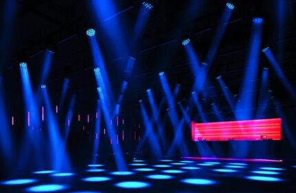 Nightclub scene at The Miami Beach EDITION, a gay-friendly hotel. Blue spotlights illuminate the dance floor and red bar.