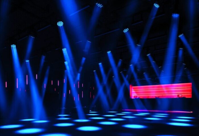 Nightclub scene at The Miami Beach EDITION, a gay-friendly hotel. Blue spotlights illuminate the dance floor and red bar.