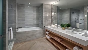 W South Beach gay-friendly hotel bathroom. Features a double sink, large mirror, bathtub, and shower. The gray and white tile gives it a modern look.