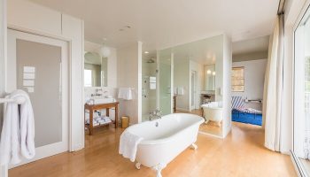 The Standard Miami gay-friendly hotel bathroom. Clawfoot tub, shower, sink, and lounger visible. Luxury gay travel accommodations.