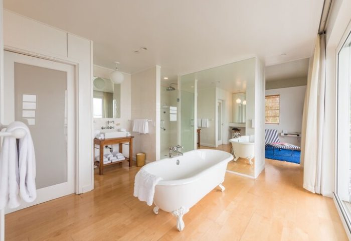 The Standard Miami gay-friendly hotel bathroom. Clawfoot tub, shower, sink, and lounger visible. Luxury gay travel accommodations.