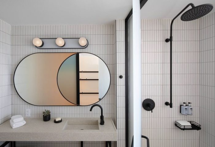 Moxy Miami South Beach gay-friendly hotel bathroom. Features a unique mirror, modern sink, and shower with black fixtures. Chic design.