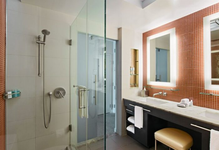 Hotel Breakwater South Beach bathroom. Shower and double vanity with orange mosaic tile. Gay-friendly hotel with modern design.