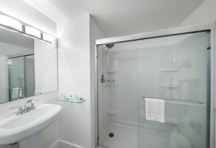 President Hotel gay-friendly bathroom. Modern, all-white design with glass shower, sink, and mirror. Ideal for gay men's travel.