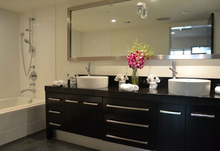 Posh South Beach gay-friendly hotel bathroom. The modern bathroom features dual sinks, a large mirror, and a bathtub with a shower.