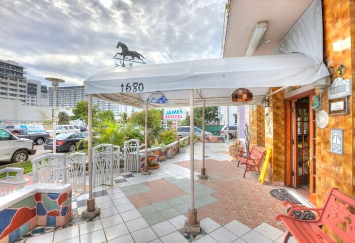 James Hotel entrance, a gay-friendly hotel. Exterior view with horse weather vane, colorful tiles, and tropical plants. Perfect for gay travel.