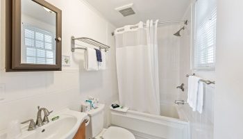 Wicker Guesthouse gay-friendly hotel bathroom. White tile, sink, toilet, tub with shower. Clean, bright, and welcoming for gay travelers.