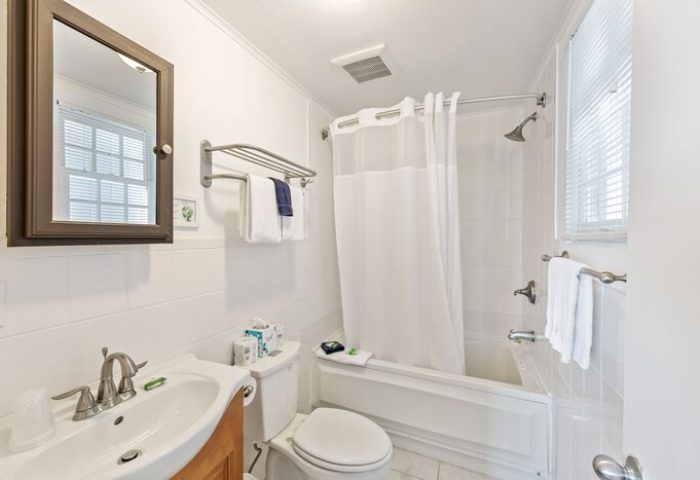 Wicker Guesthouse gay-friendly hotel bathroom. White tile, sink, toilet, tub with shower. Clean, bright, and welcoming for gay travelers.