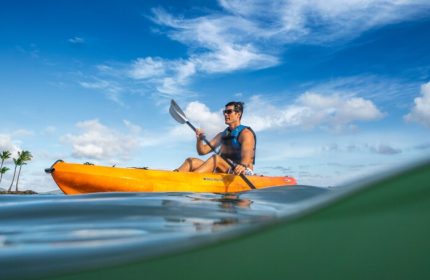 Gay-friendly The Kahala Hotel and Resort: man kayaking. Water view of a man in an orange kayak. Gay travel advice for Hawaii vacations.