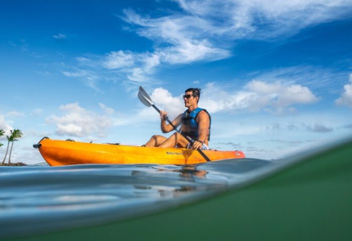 Gay-friendly The Kahala Hotel and Resort: man kayaking. Water view of a man in an orange kayak. Gay travel advice for Hawaii vacations.