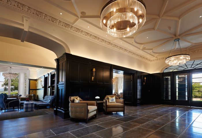 Cameron House on Loch Lomond's gay-friendly hotel interior. Elegant lobby with chandeliers, seating, and dark wood paneling. Upscale travel.