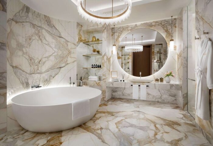 Atlantis The Royal gay-friendly hotel bathroom. Oval tub, round mirror, marble walls, chandelier. Luxury travel for gay men.