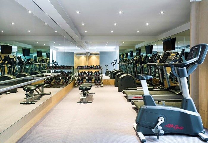 99 Bonham gay-friendly hotel gym. Fitness center with weights, treadmills, ellipticals, and stationary bikes. Mirrors line the wall.