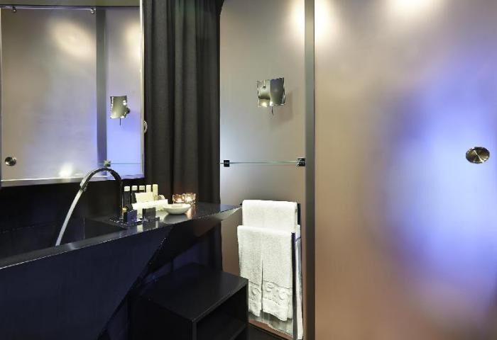 9HOTEL MERCY gay-friendly hotel bathroom. Sleek design with black vanity, modern fixtures, and soft lighting. Towels are neatly arranged.