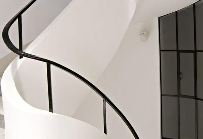 Interior of A For Athens Hotel, a gay-friendly hotel. White spiral staircase with black metal railing and a window with black frame.
