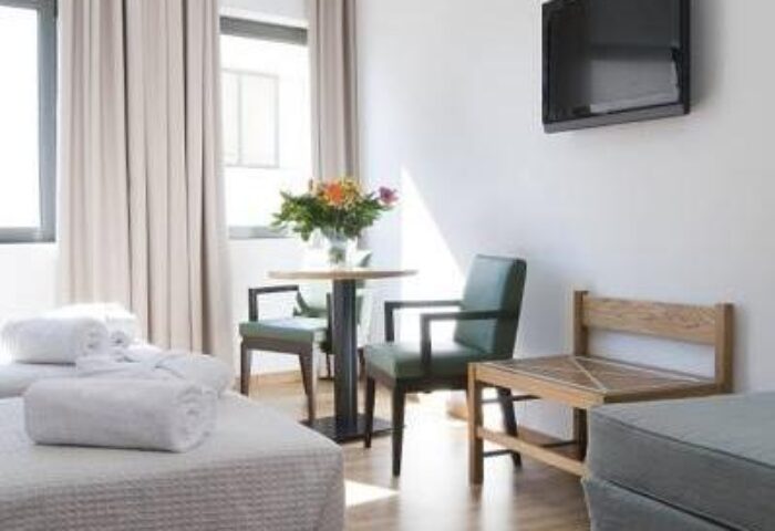 Gay-Friendly A For Athens Hotel room. Clean design, with a table, chairs, and TV. Ideal for gay men travelers in Athens.
