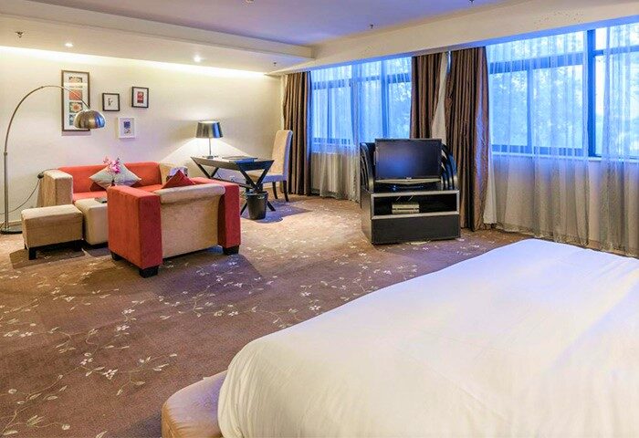 A. HOTEL gay-friendly hotel room. Interior view with bed, seating area, desk, and TV. Modern design for gay men's travel.