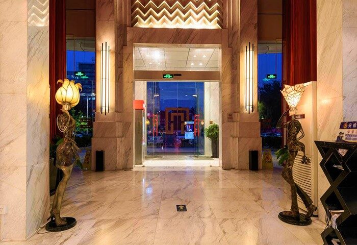 A. HOTEL entrance. Gay-friendly hotel lobby with marble floors, statues holding lamps, and glass doors. Modern design for gay men travelers.