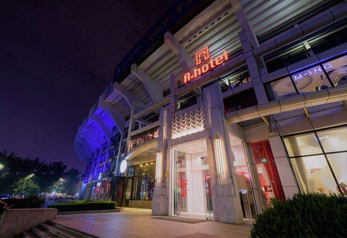 A. HOTEL: Exterior view of a gay-friendly hotel at night. Modern architecture, illuminated signage. Gay travel accommodations.