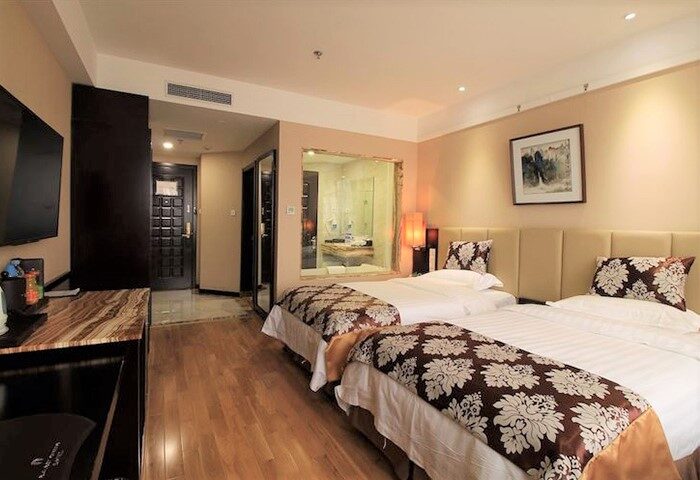 AC Embassy Hotel gay-friendly room. Two beds with floral pattern, bathroom view, and modern decor. Ideal for gay men travel in luxury.