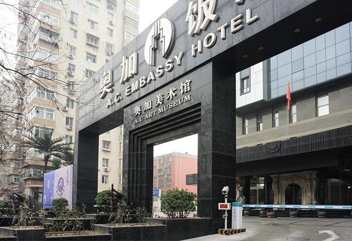 Entrance of AC Embassy Hotel, a gay-friendly hotel. The hotel's name is displayed prominently above the entrance. The hotel also has an art museum.