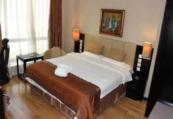 AC Embassy Hotel room interior. Gay-friendly hotel featuring a comfortable bed, modern decor, and warm lighting. Ideal for gay men's travel.