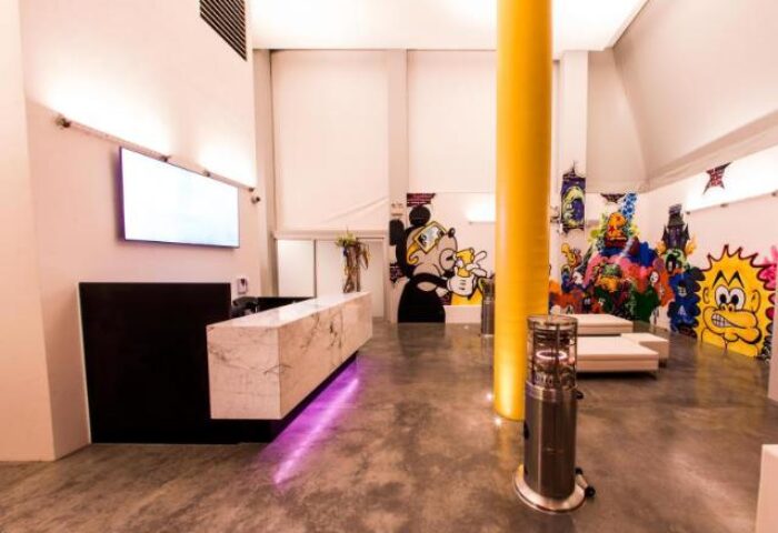 ADGE Apartments' lobby. A gay-friendly hotel with colorful cartoon murals, a marble reception desk, and modern design. Great for gay travel.