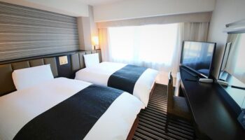 APA Hotel Shinjuku-Gyoemmae gay-friendly room. Twin beds, desk, and TV. Modern decor, clean lines. A comfortable stay in Tokyo's vibrant Shinjuku.