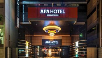 Night view of APA Hotel Shinjuku-Gyoemmae, a gay-friendly hotel in Tokyo. The hotel's entrance is illuminated, creating a welcoming atmosphere.