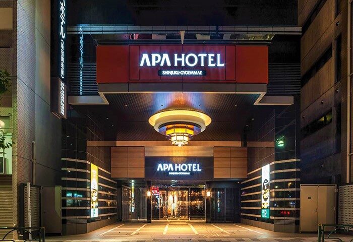 Night view of APA Hotel Shinjuku-Gyoemmae, a gay-friendly hotel in Tokyo. The hotel's entrance is illuminated, creating a welcoming atmosphere.