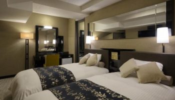 Gay-friendly APA Hotel Shinjuku-Kabukicho Tower room. Twin beds, desk, and mirror. A comfortable stay in Tokyo's vibrant district.