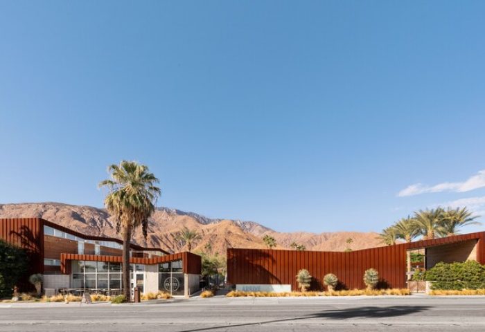 ARRIVE Palm Springs hotel exterior. Gay-friendly hotel with modern architecture, palm trees, and mountain backdrop. Great for gay travel.