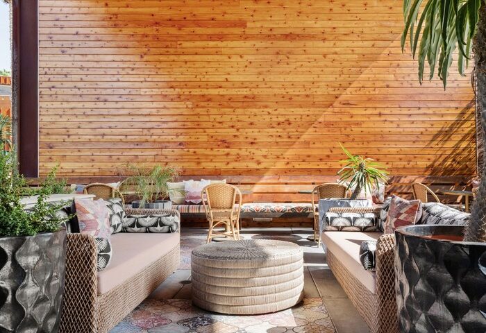 ARRIVE Palm Springs gay-friendly hotel outdoor lounge area. Stylish seating, wood wall, patterned floor. Ideal for gay travel relaxation.