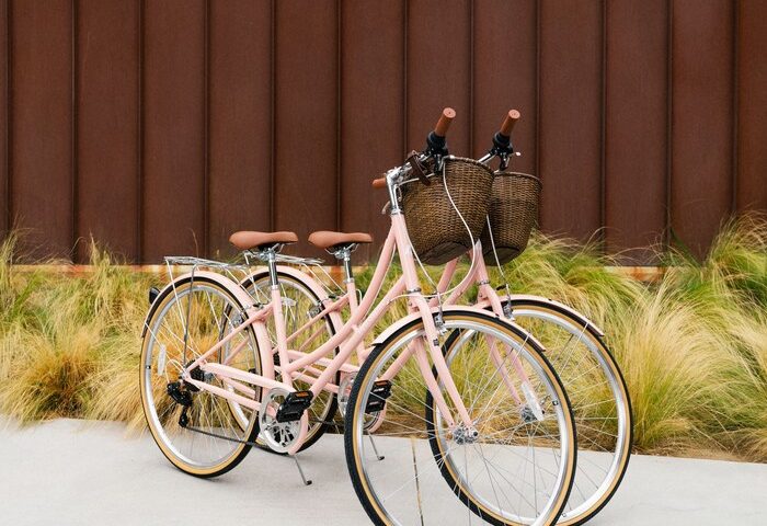 Two pink bicycles at ARRIVE Palm Springs, a gay-friendly hotel. Bikes have baskets and brown seats. Great for exploring Palm Springs.