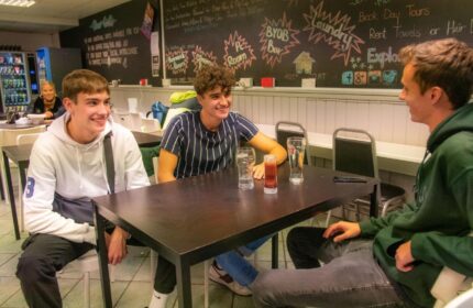 Gay-friendly Abbey Court Hostel: Three young men chatting at a table, enjoying drinks. A relaxed atmosphere for gay travelers. Socializing at the hostel.