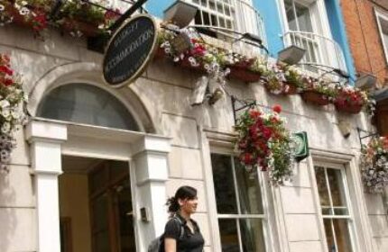 Abbey Court Hostel exterior. Gay-friendly hotel with flowers, sign, and woman. Budget accommodation for gay men travelers in Dublin.