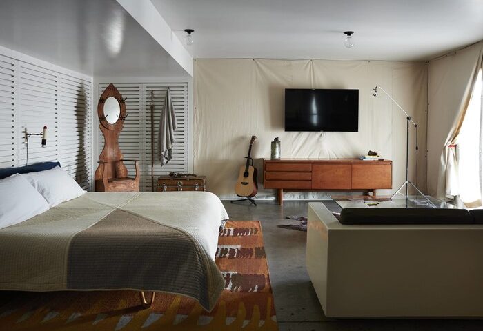 Ace Hotel and Swim Club Palm Springs room. Gay-friendly hotel interior: bed, TV, guitar, mid-century modern furniture, and unique decor.