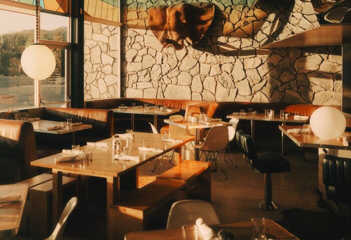 Ace Hotel Palm Springs restaurant interior. Tables, booths, stone wall, and stained glass. Gay-friendly hotel dining for gay men travel.