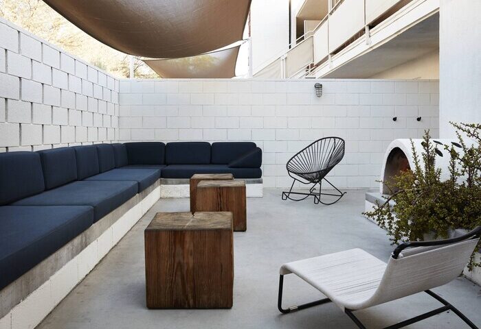 Ace Hotel & Swim Club Palm Springs patio. Modern outdoor furniture: sofa, chairs, & wood tables. Gay-friendly hotel design.